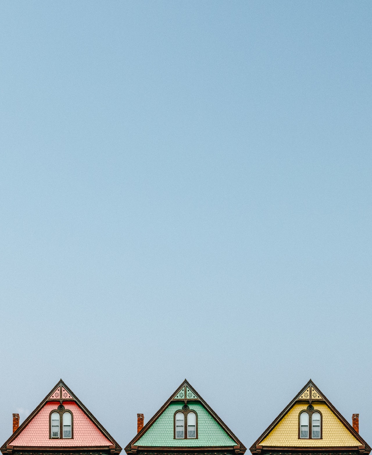A picture of three roofs one pink, one green, one yellow
