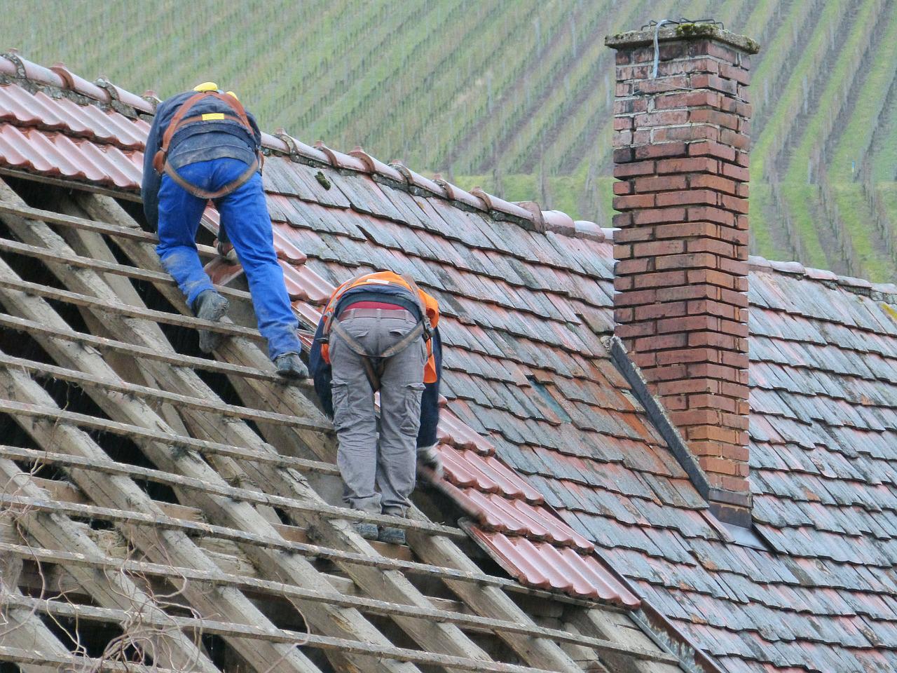 Two men adding shingles to a partially finished roof